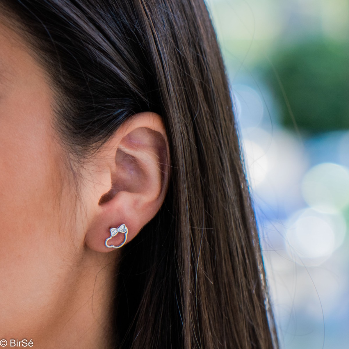 Cute children's earrings, made of shiny rhodium silver, depicting a bear's head with a ribbon of zircons. Earrings are a suitable gift for a child of any age.