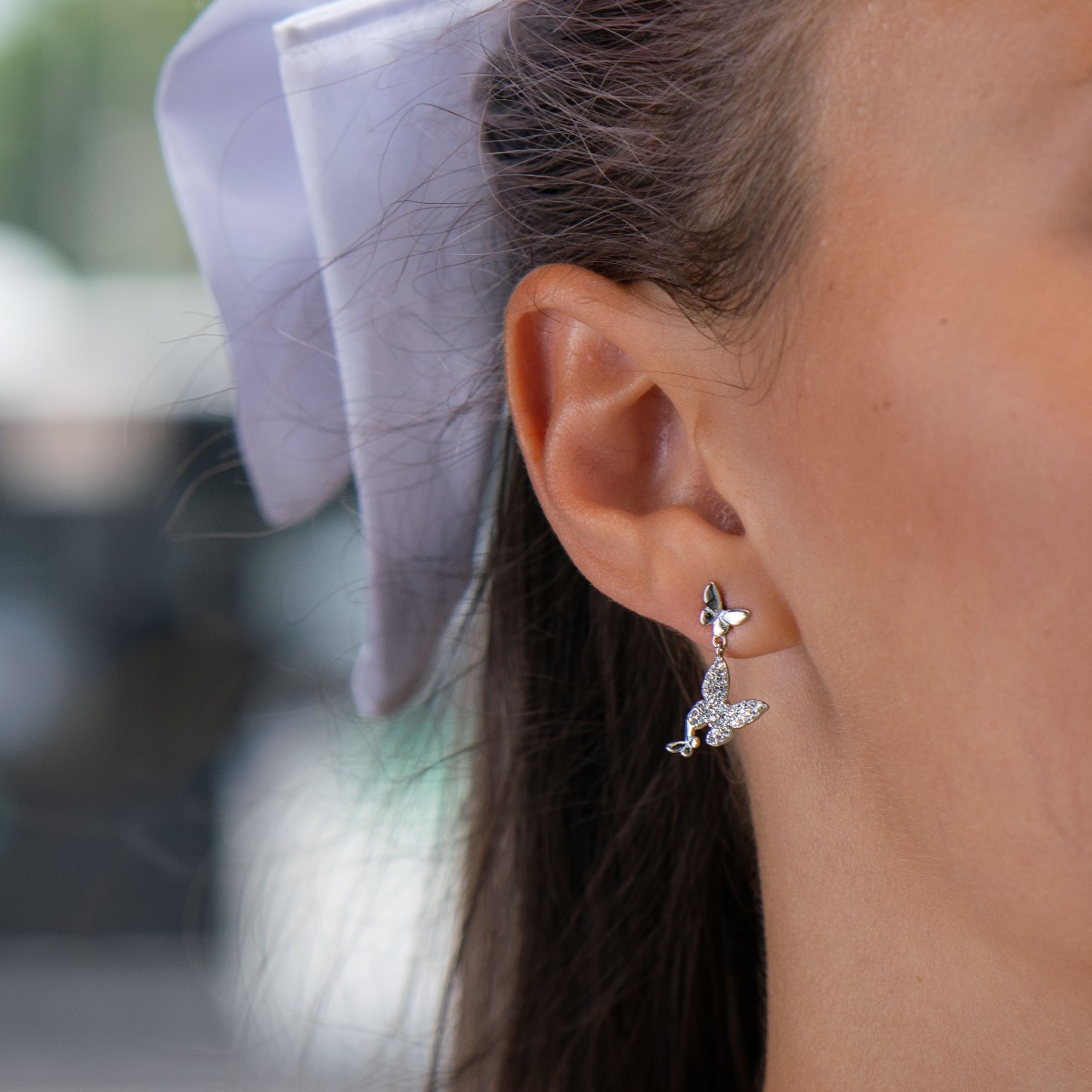 Elegant women's earrings made of rhodium-plated fine silver. Exquisite jewelry with dangling butterflies that are decorated with delicate zircons, stylish design and comfortable pin fastening. A wonderful gift for your beloved woman.