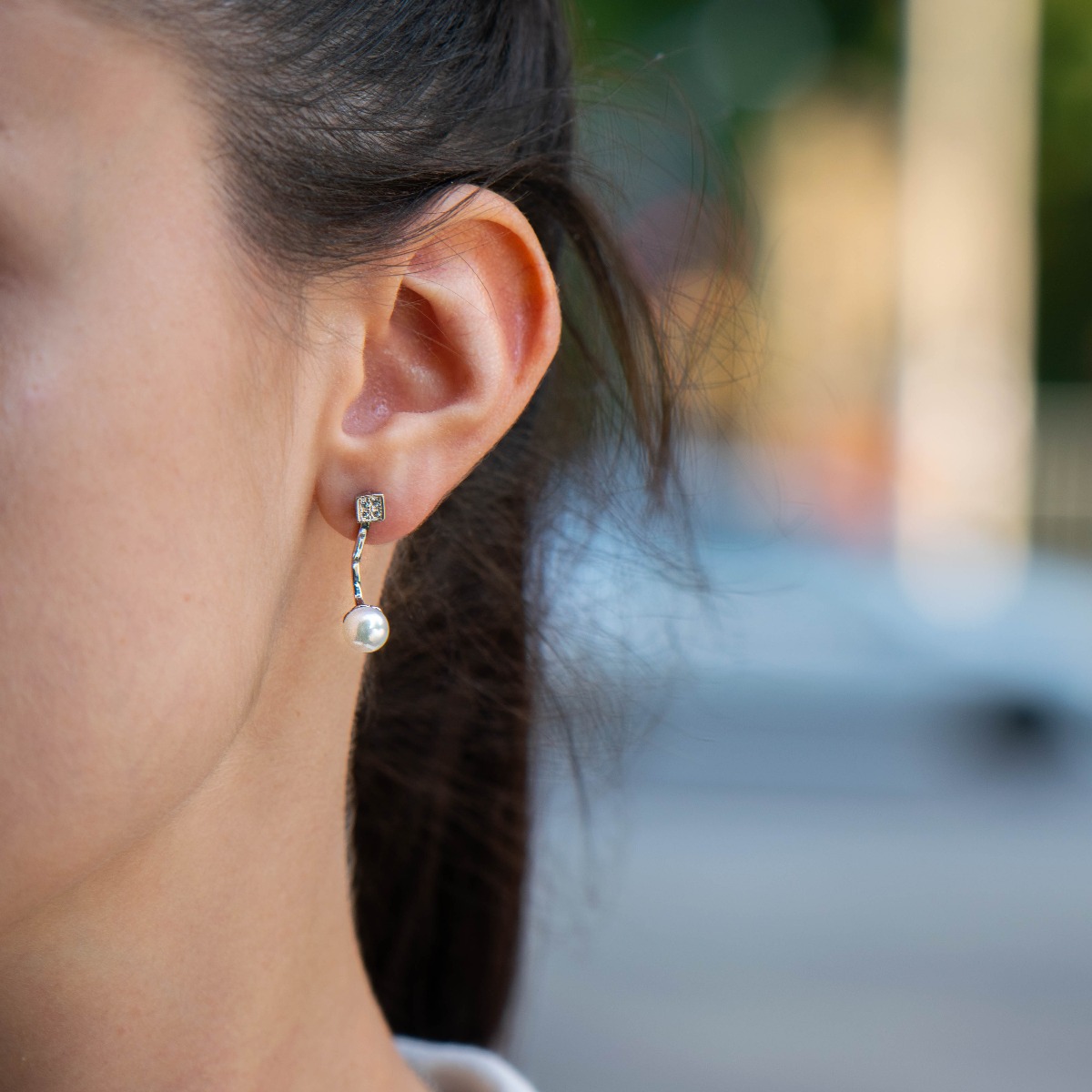 A beautiful model of women's earrings, entirely made of fine rhodium silver, with a comfortable and secure pin fastening. Delicate, sparkling zircons adorn the earpiece, while a fine pearl elegantly protrudes below. Charming and suitable for any occasion.