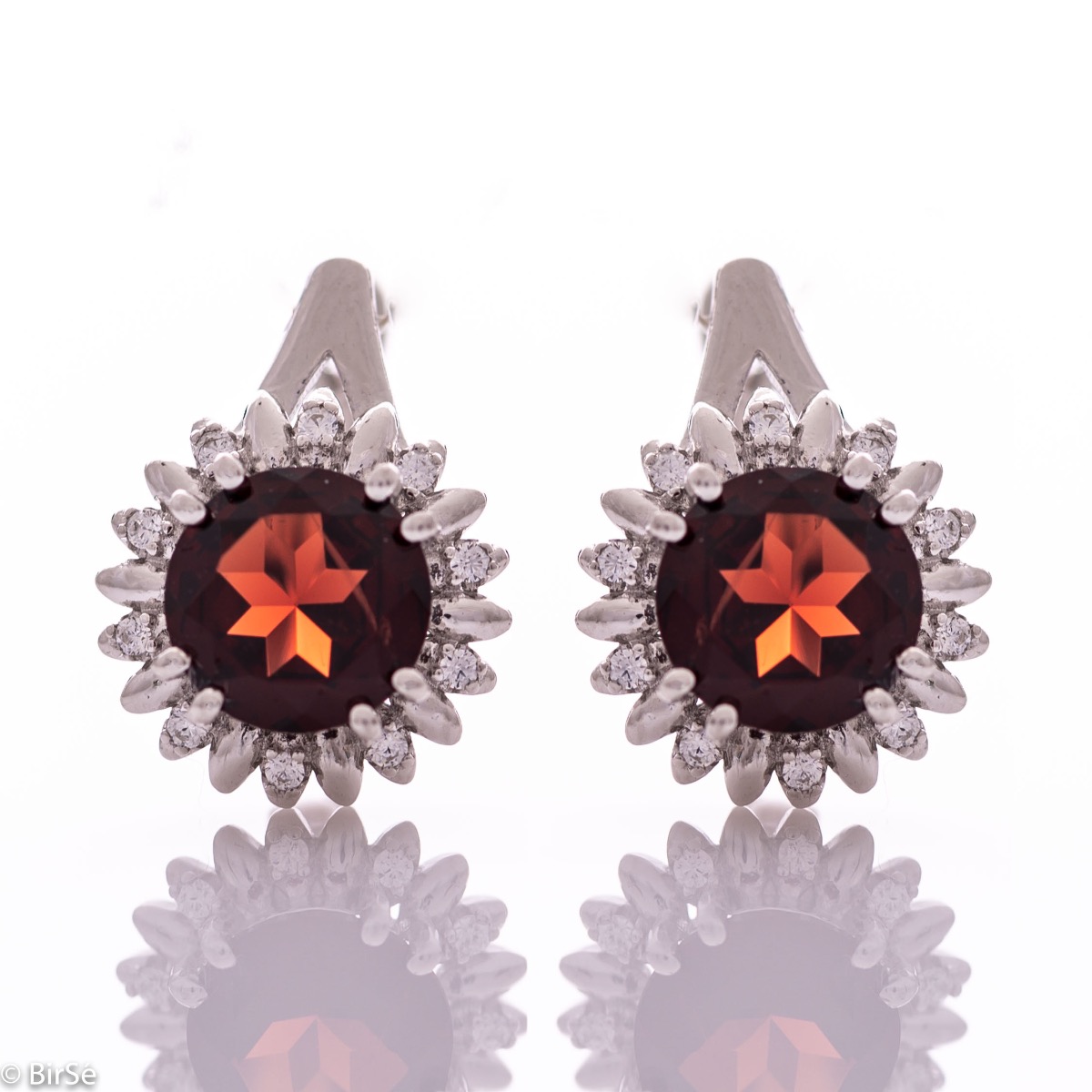 Extremely elegant ladies' earrings with English fastening and precise craftsmanship combining rhodium-plated silver with radiant natural garnet and sparkling zircons. They can be combined with a pendant and a ring of the same model.