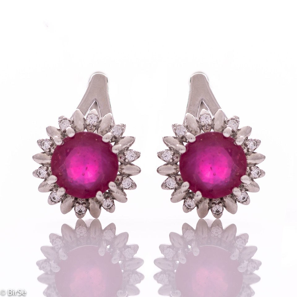 Extremely elegant ladies' earrings with English fastening and precise craftsmanship combining rhodium-plated silver with radiant natural ruby ​​and sparkling zircons. They can be combined with a pendant and a ring of the same model.