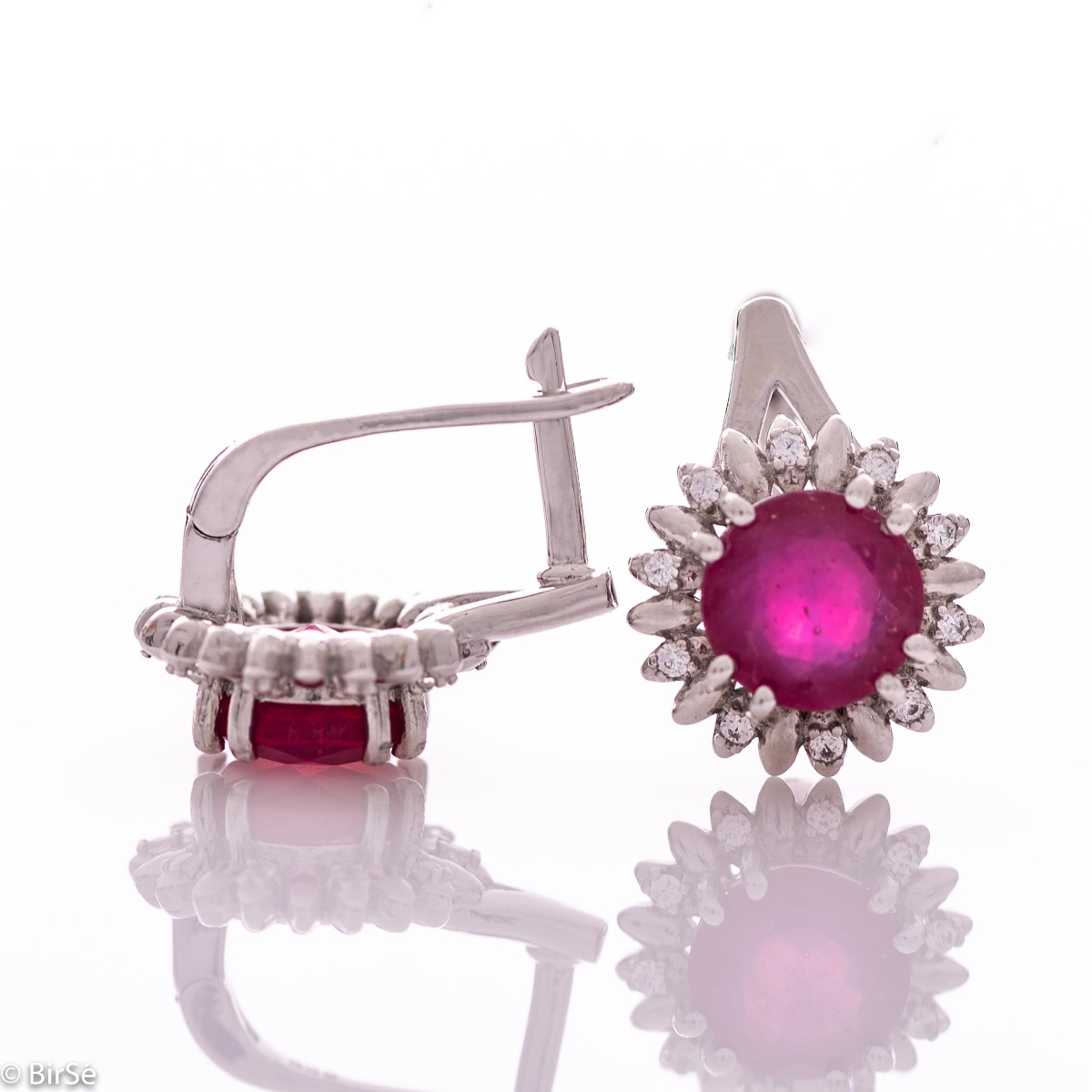 Extremely elegant ladies' earrings with English fastening and precise craftsmanship combining rhodium-plated silver with radiant natural ruby ​​and sparkling zircons. They can be combined with a pendant and a ring of the same model.