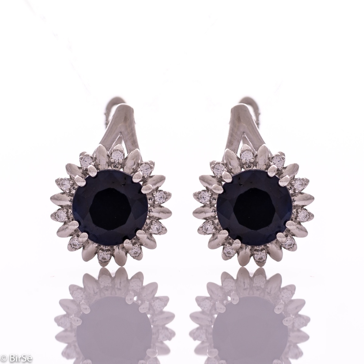 Extremely elegant ladies' earrings with English fastening and precise craftsmanship combining rhodium-plated silver with radiant natural sapphire and sparkling zircons. They can be combined with a pendant and a ring of the same model.