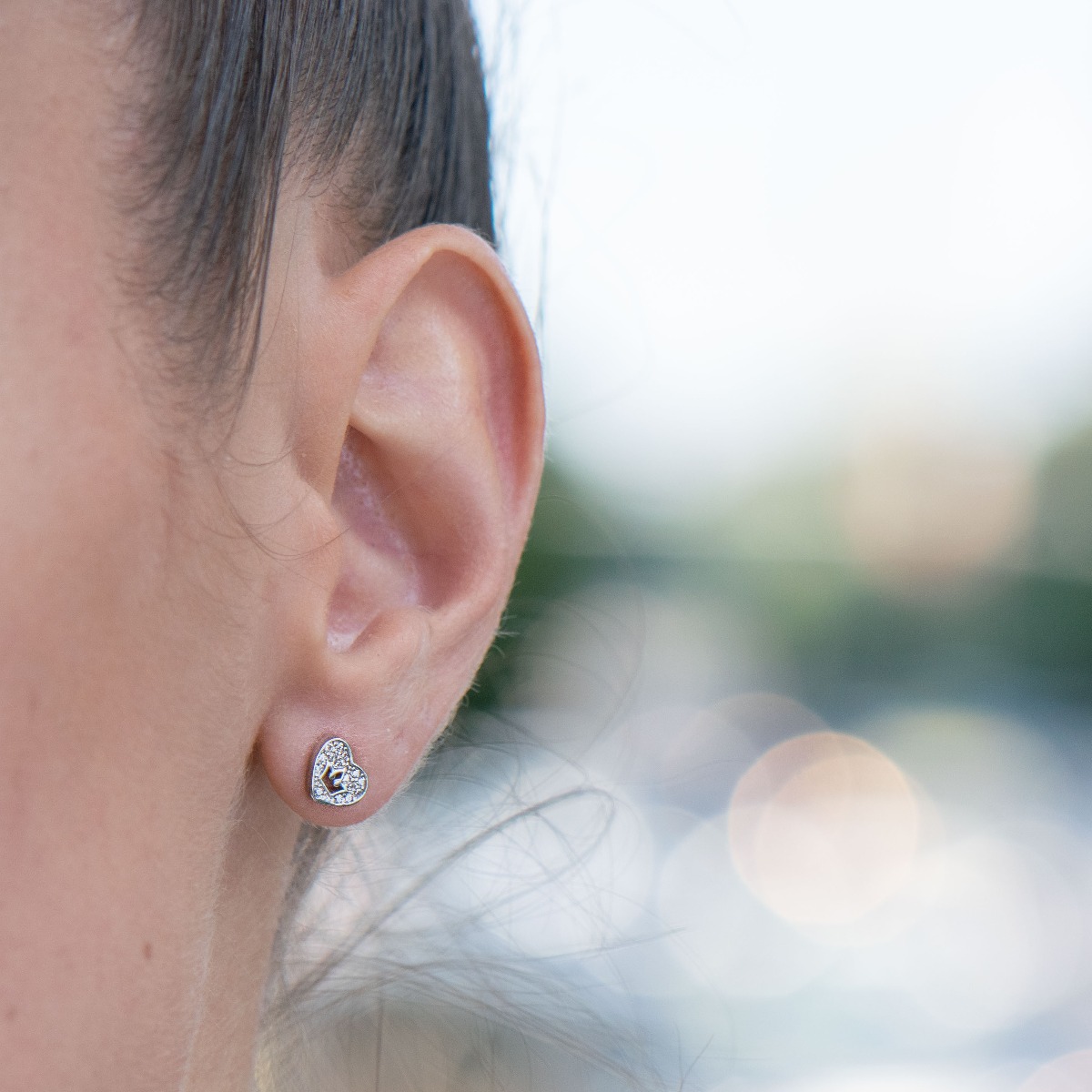 Captivating earrings, combining the charm of fine rhodium silver with the sparkle of zircons. The combination of the two forms hearts, in the center of which a royal crown stands proudly.