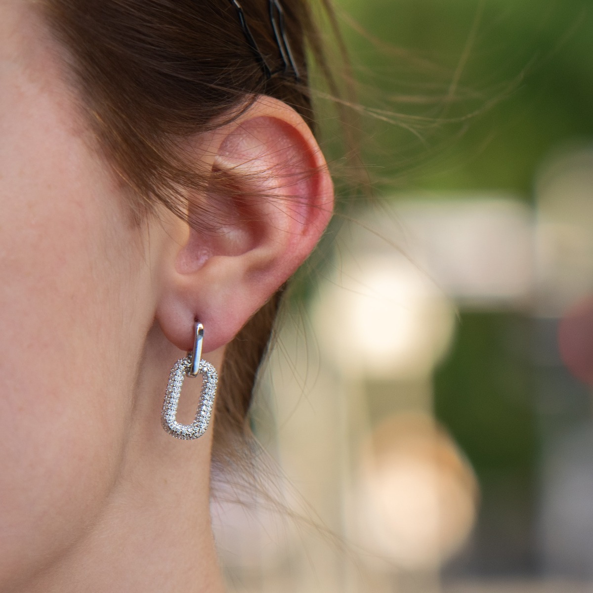 Charming women's earrings made entirely of fine rhodium silver with a dangling element elegantly decorated with fine zircons. The clasp is with a pin, and the earrings make a suitable gift for any occasion.