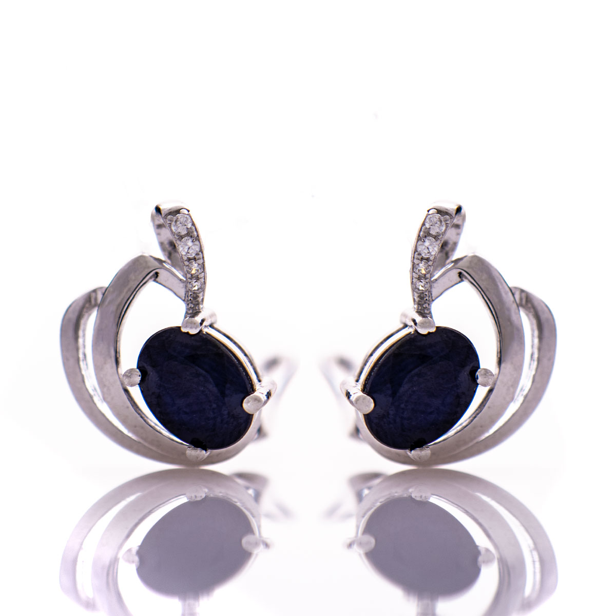 Sophisticated women's earrings with a non-standard and modern design, made entirely of beautiful rhodium-plated silver, complemented by a radiant natural sapphire stone and delicate zircons. In an exclusive sterling silver pendant and ring set.