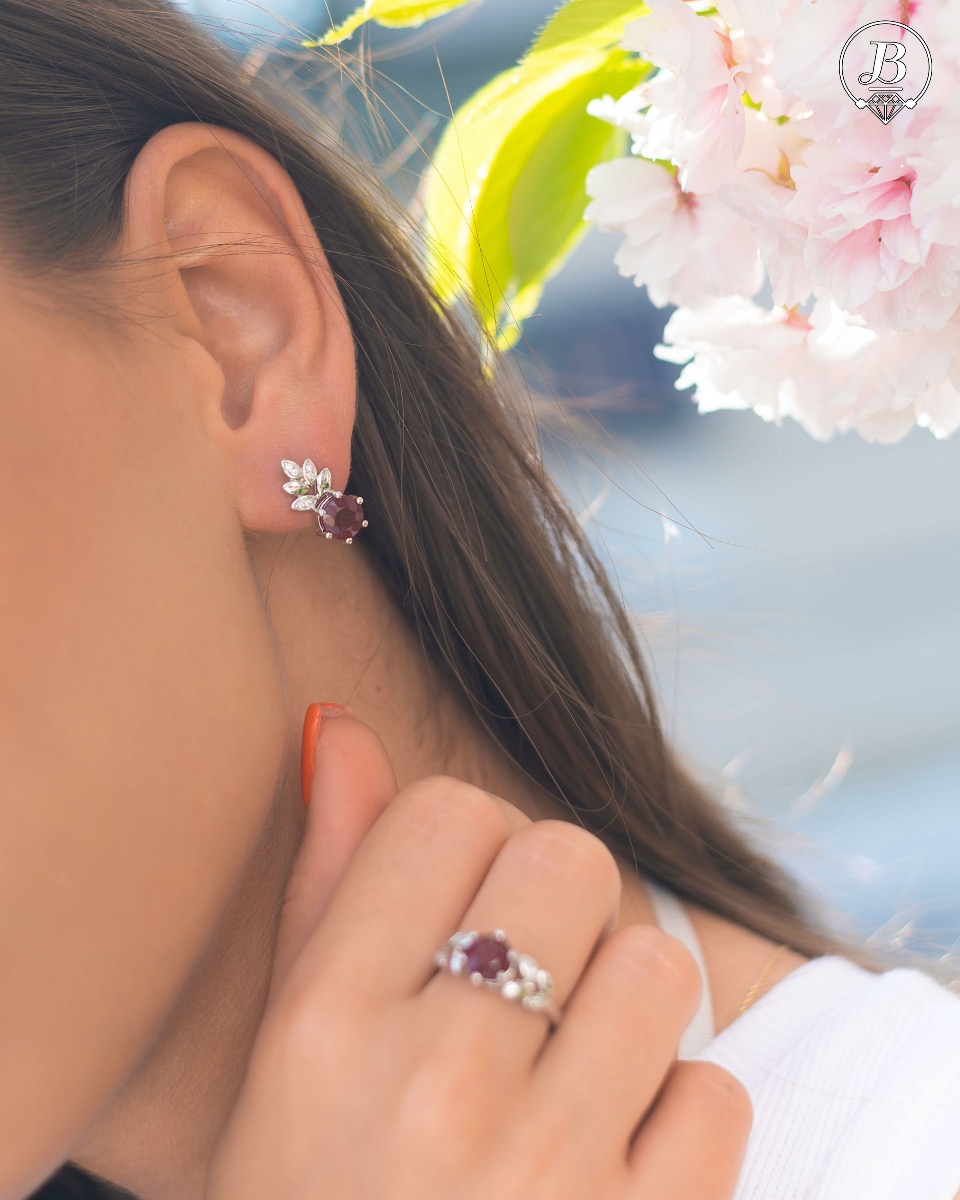 Delicate ladies' earrings with an English clasp and an exclusive design combining a radiant natural garnet surrounded by petals of zircons and made entirely of rhodium-plated silver. They can be combined with a pendant and a ring of the same model.