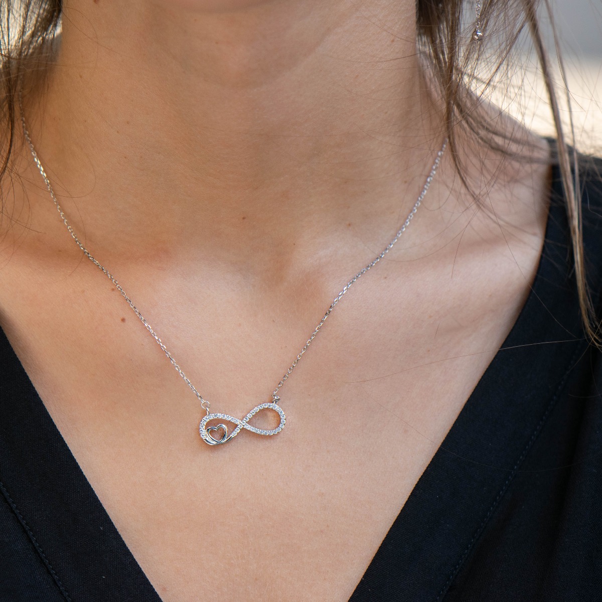 An exquisite women's necklace with precision craftsmanship entirely of rhodium-plated silver, combining a delicate infinity shape, intertwined with a heart and sparkling zircons.