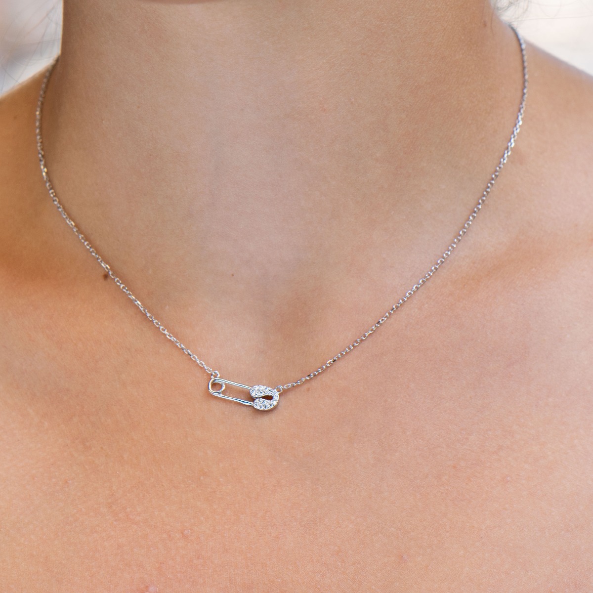 A spectacular necklace with an exquisite shape of a delicate safety pin, complemented by fine, sparkling zircons and made entirely of rhodium-plated silver.