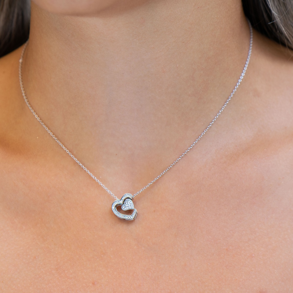 An exquisite women's necklace with precise craftsmanship combining delicate rhodium silver with glittering zircons and the shape of two beautiful hearts.