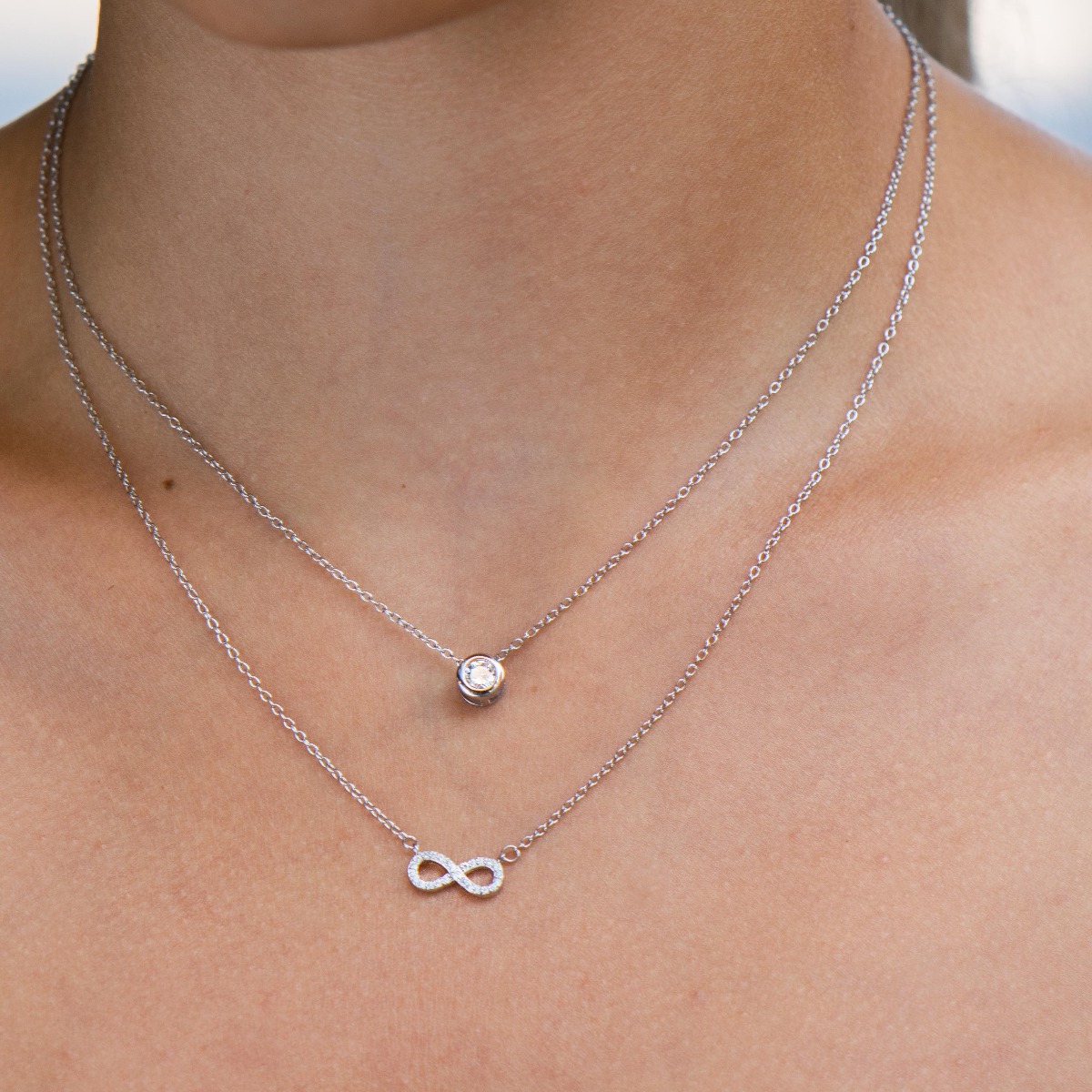 A double silver necklace with a spectacular design entirely of rhodium-plated silver and two delicate elements of a dazzling infinity and a central zircon.