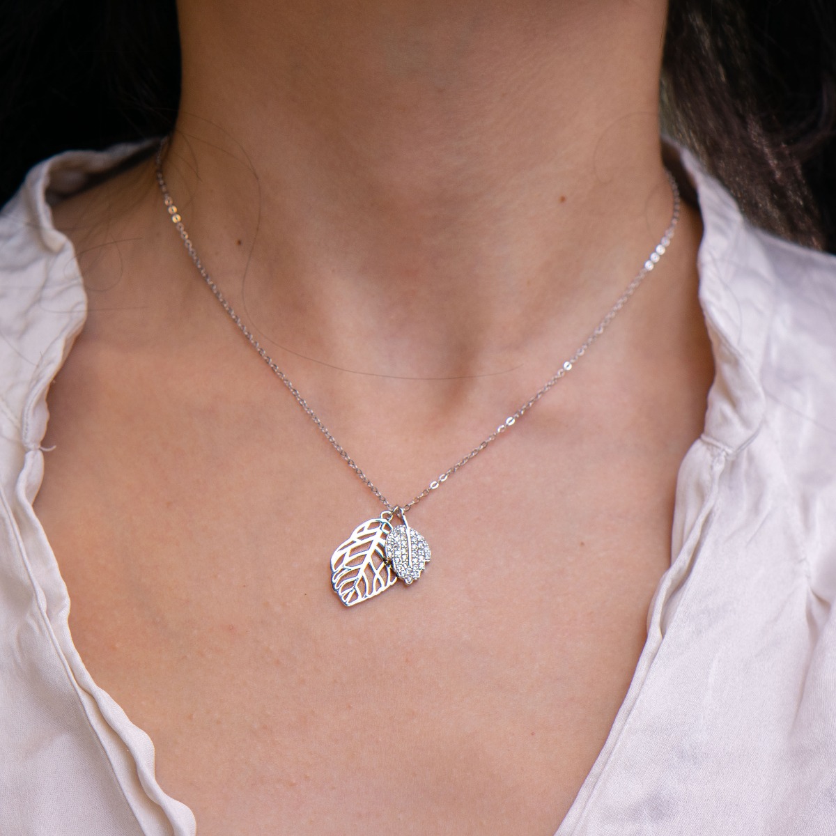 Extremely fine and delicate workmanship of a necklace of soft rhodium-plated silver in the shape of a leaf. Stylish design of the details with the addition of sparkling white zircons.