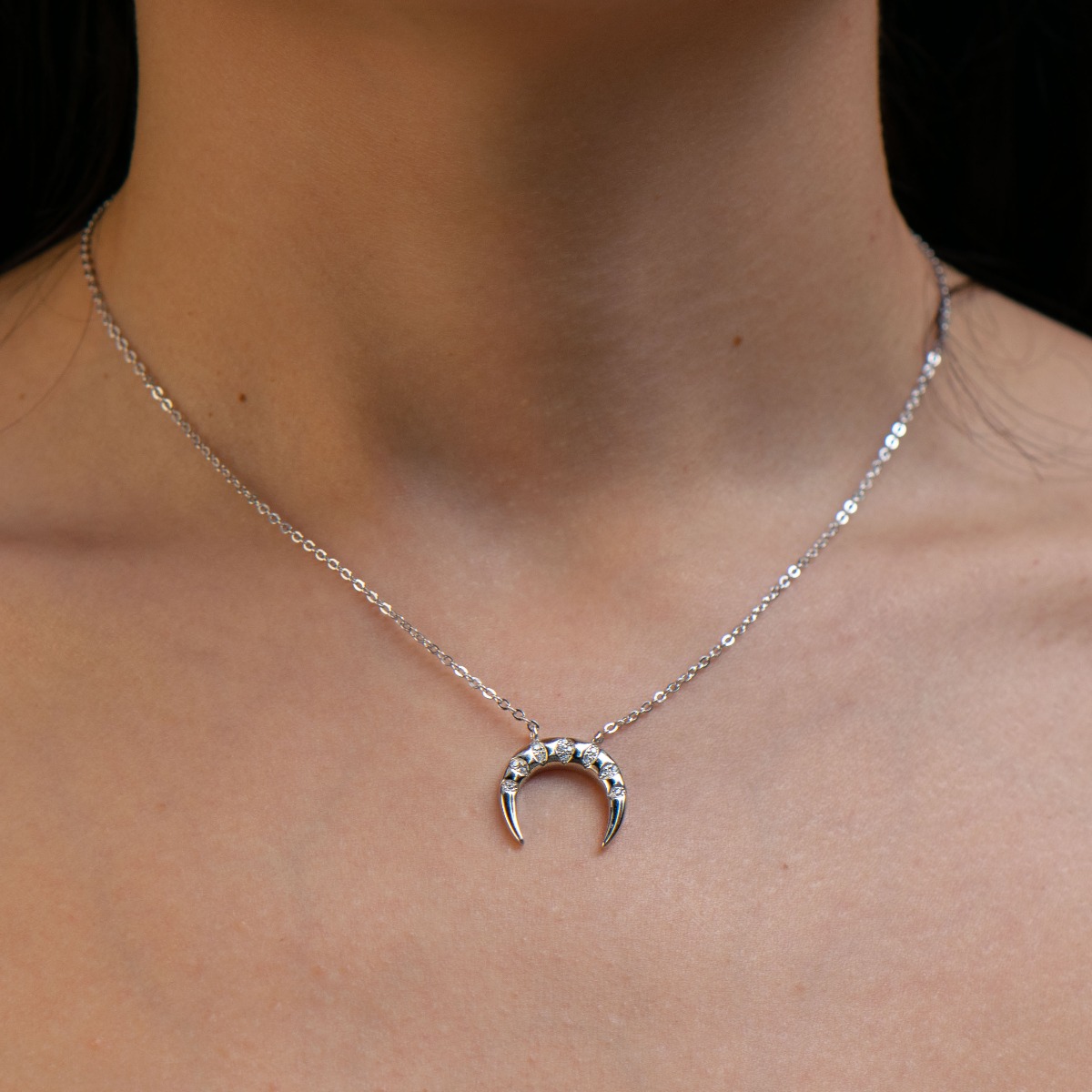 Delicate women's necklace with an exquisite design of rhodium-plated silver in the shape of a rainbow. The jewel has an elegant chain holding an element with added fine zircons. The added extension helps to adjust the length according to the client's wish