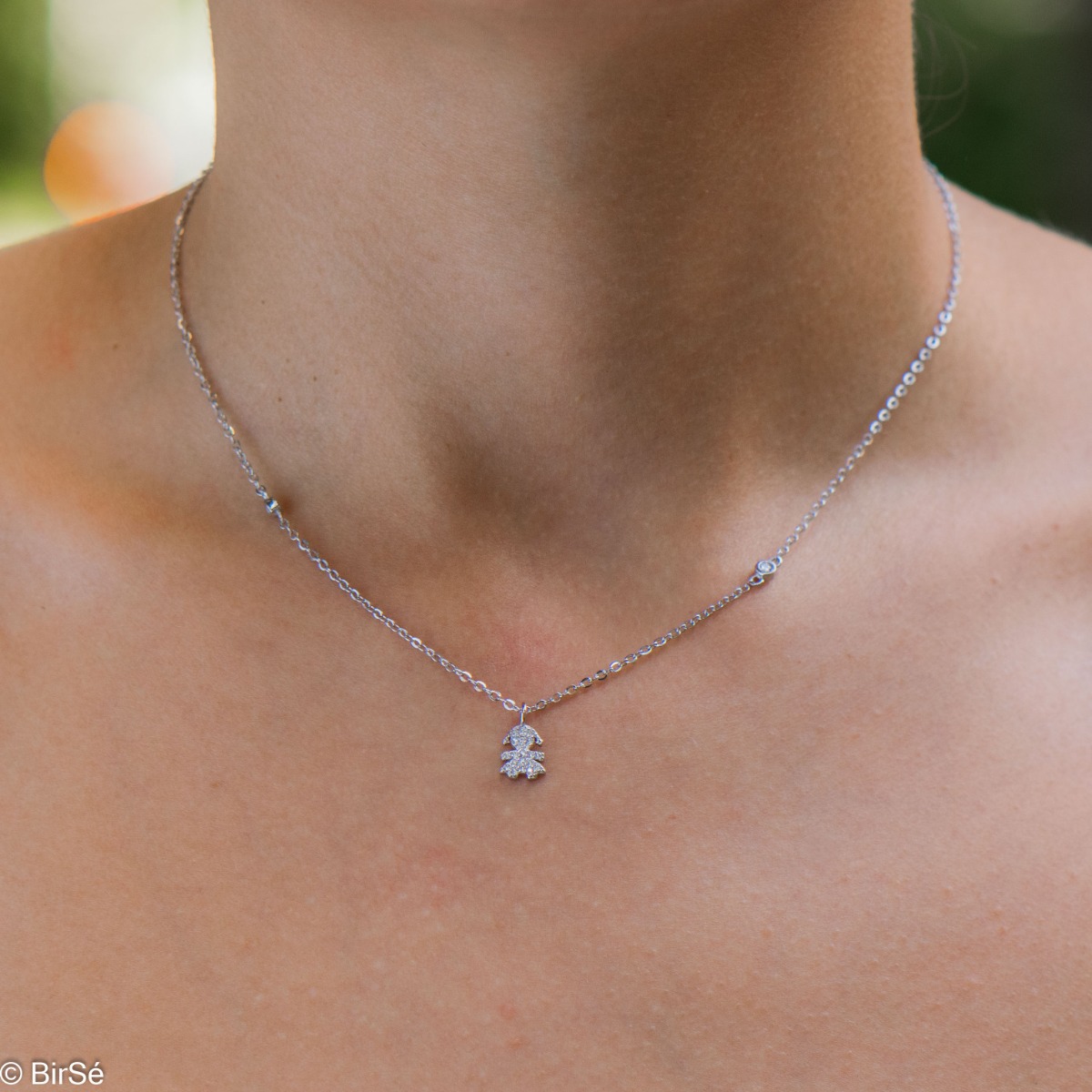 A charming delicate necklace in fine silver with a design of a little girl, studded with countless glittering zircons. The necklace is a suitable gift for a young girl or a mother of a newborn baby girl.