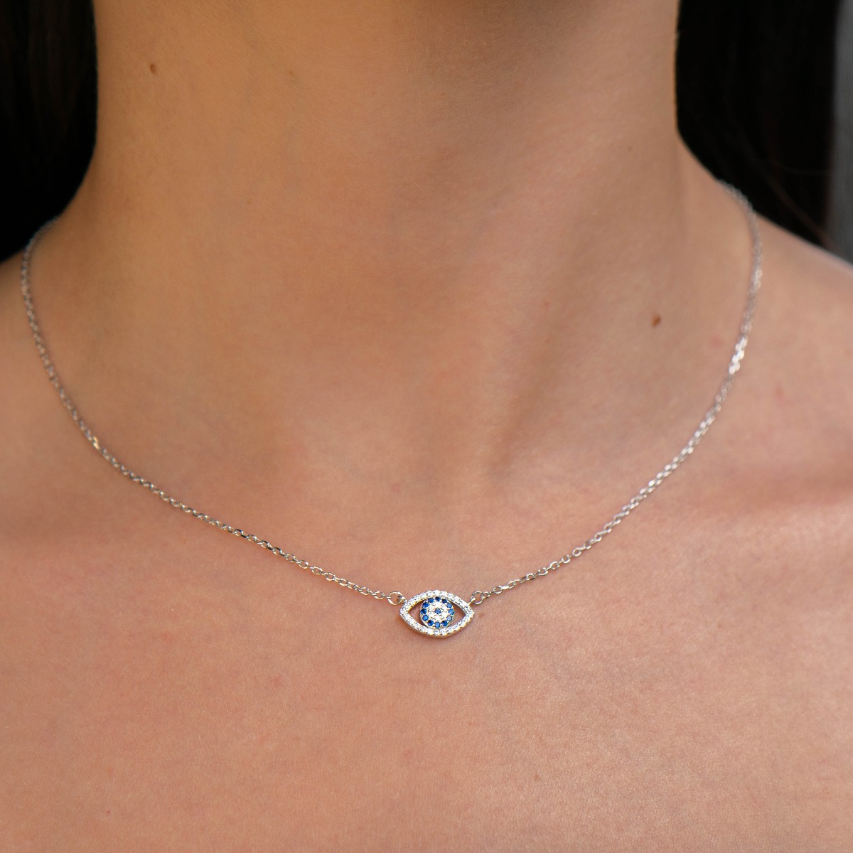 A mystical eye-shaped necklace in soft rhodium-plated silver. Gleaming white and blue zircons give the jewel a special charm, which perfectly combine with the tenderness of rhodium-plated silver.