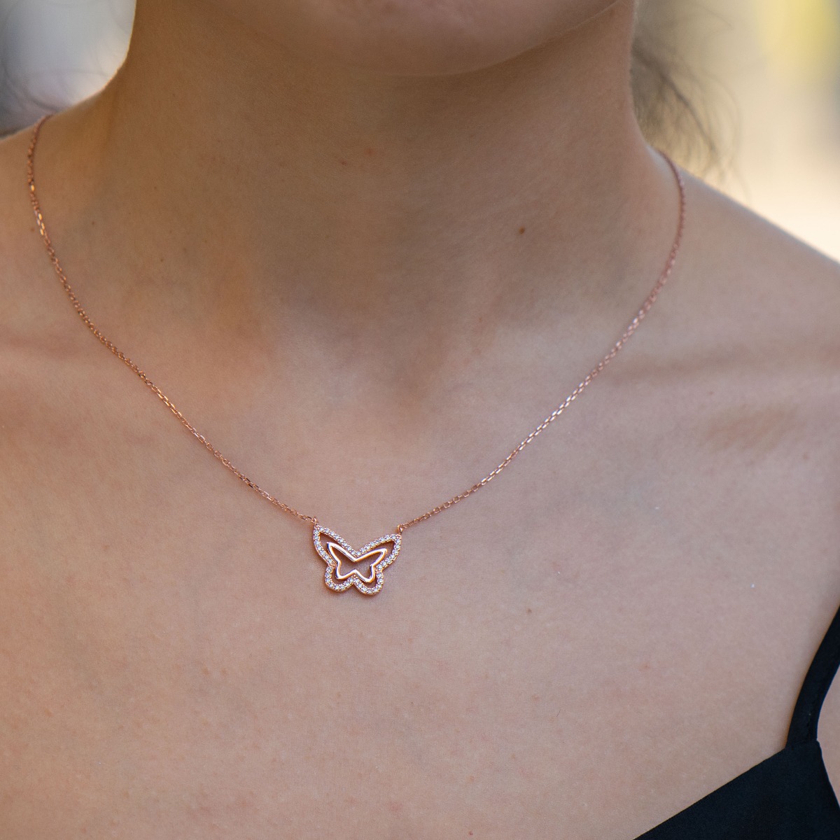 A beautiful women's necklace with a delicate butterfly, complemented by sparkling white zircons and made entirely of soft rhodium-plated rose silver.