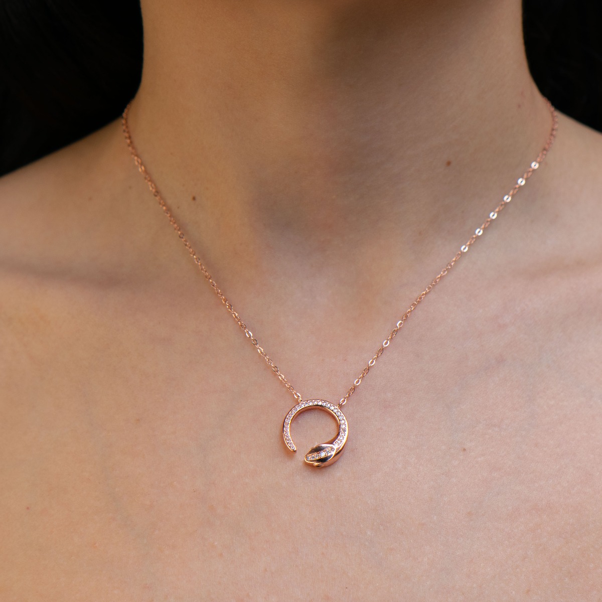 Elegant women's necklace with rose silver design. The piece of jewelery has a captivating craftsmanship - a delicate chain holding a delicate element in the shape of a snake, elegantly decorated with sparkling zircons.