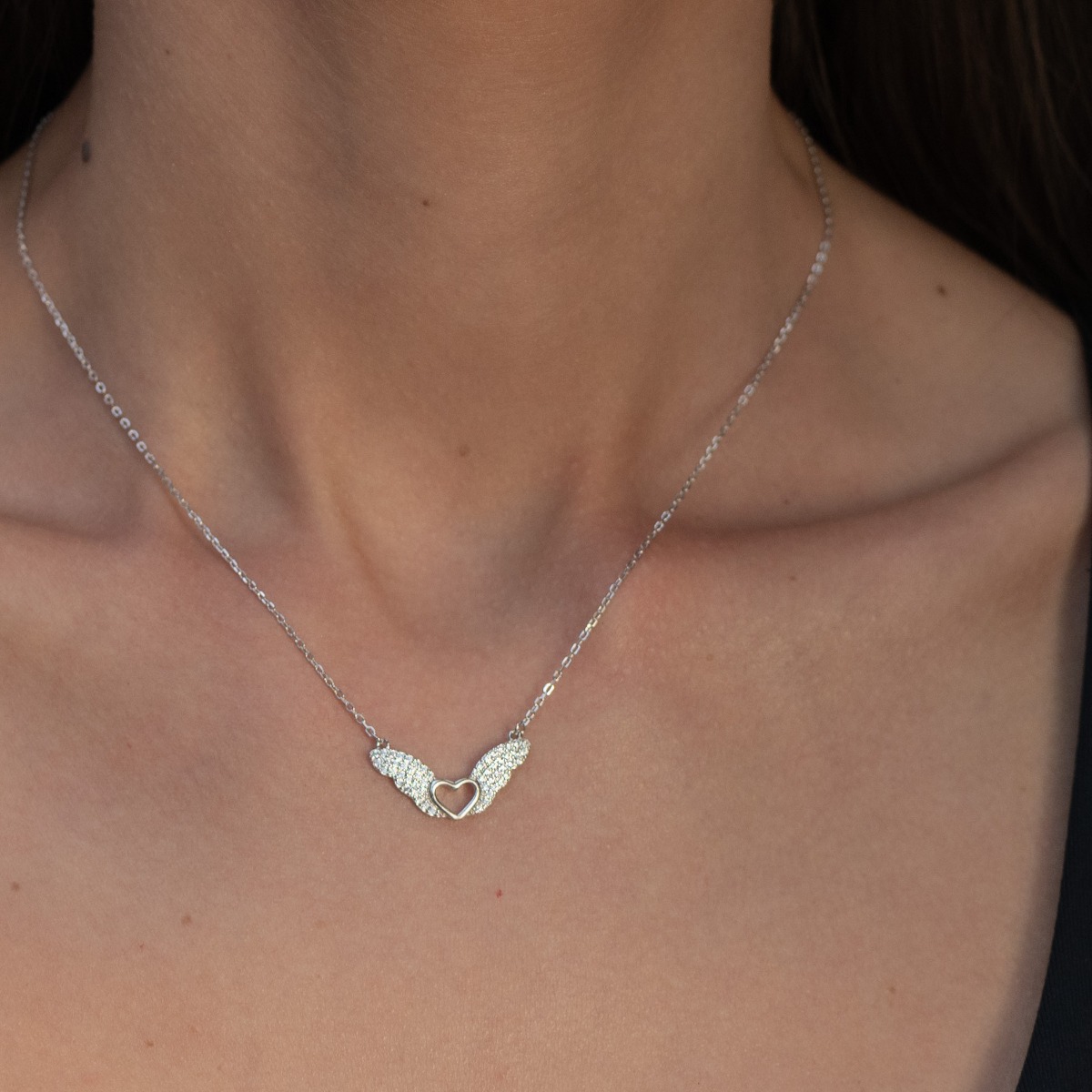 Captivating women's necklace in rhodium-plated silver with an impressive delicate heart design, complemented by two sparkling wings studded with zircons.