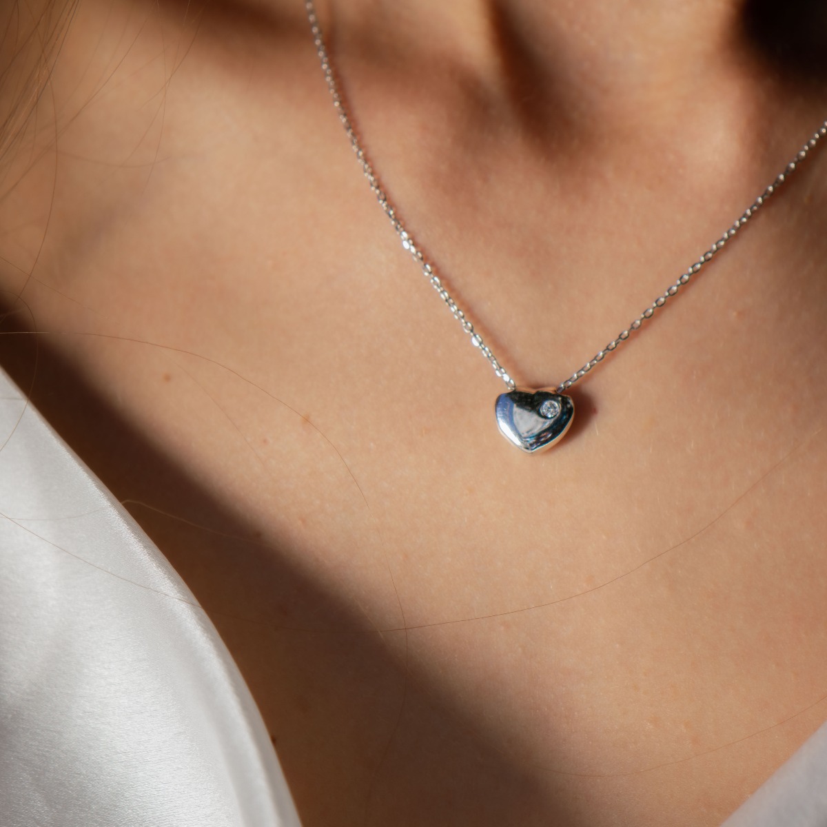 A fine women's necklace suitable for everyday life, with delicate workmanship entirely of rhodium-plated silver and a small heart complemented by a shiny zircon.