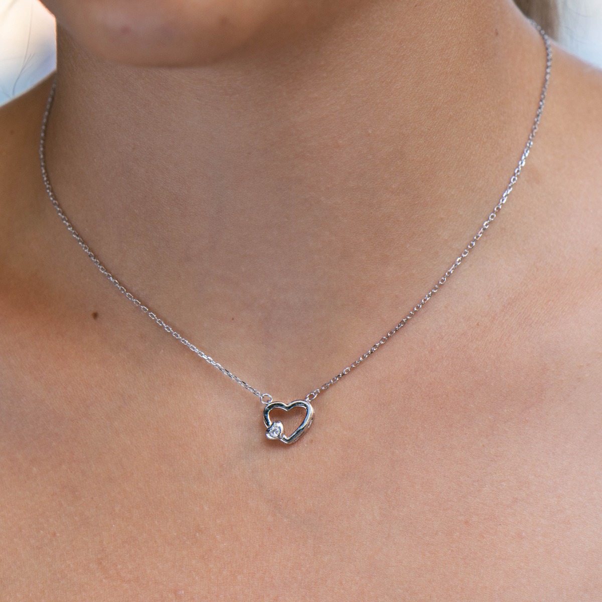 A delicate silver necklace with a heart and a sparkling zircon, made entirely of refined rhodium-plated silver.