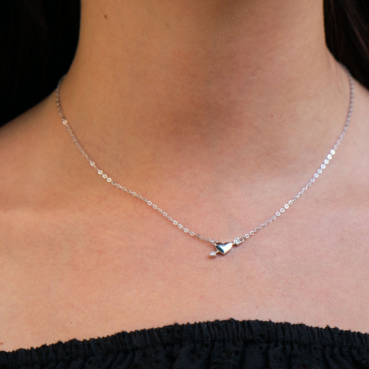 An elegant women's silver necklace with an elegantly crafted heart pierced by the arrow of love. Delicate zircons complete the charm of the jewel.