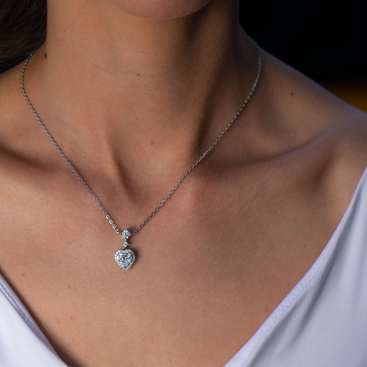 Delicate silver necklace in the shape of an exquisitely sculpted heart. A stylish work of art from a fine combination of rhodium-plated silver with sparkling zircons.