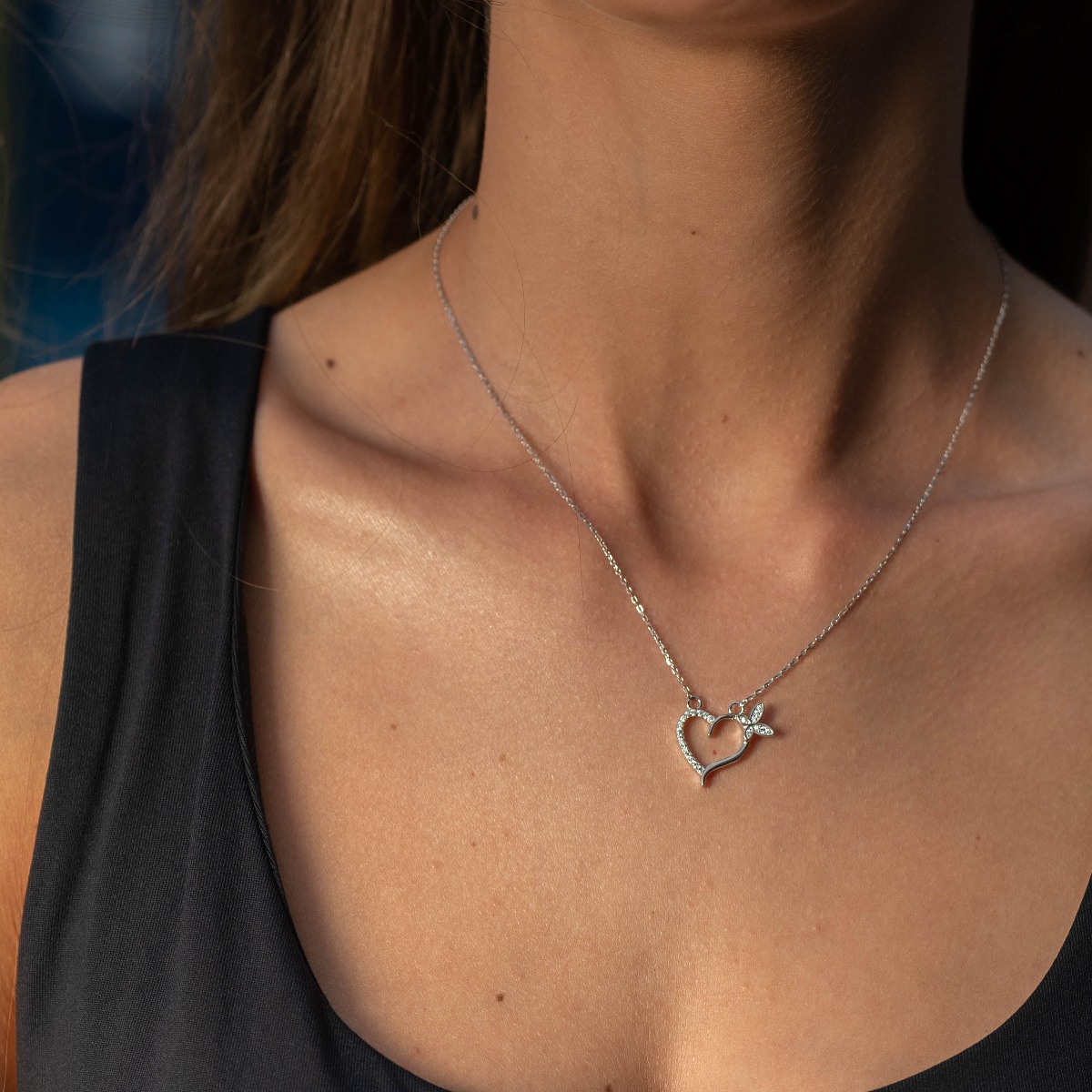 A delicate women's necklace with a heart and a butterfly and exquisite workmanship entirely of rhodium-plated silver, complemented by sparkling zircons.