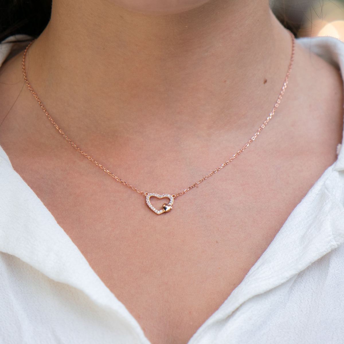 Temptingly crafted women's fine rose silver necklace with two hearts and countless glittering zircons. The jewelry is suitable for romantic ladies and also carries symbolism for expectant mothers carrying the new life under their heart.