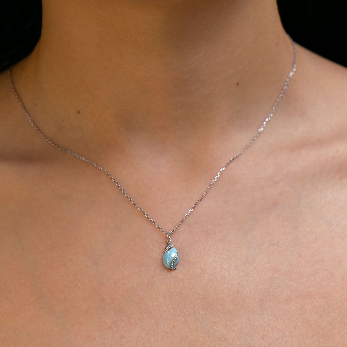 Delicate women's necklace with an exquisite rhodium silver pendant design. The jewelry features an elegant chain holding an exotic element with a captivating sea blue opal and added fine zircons.