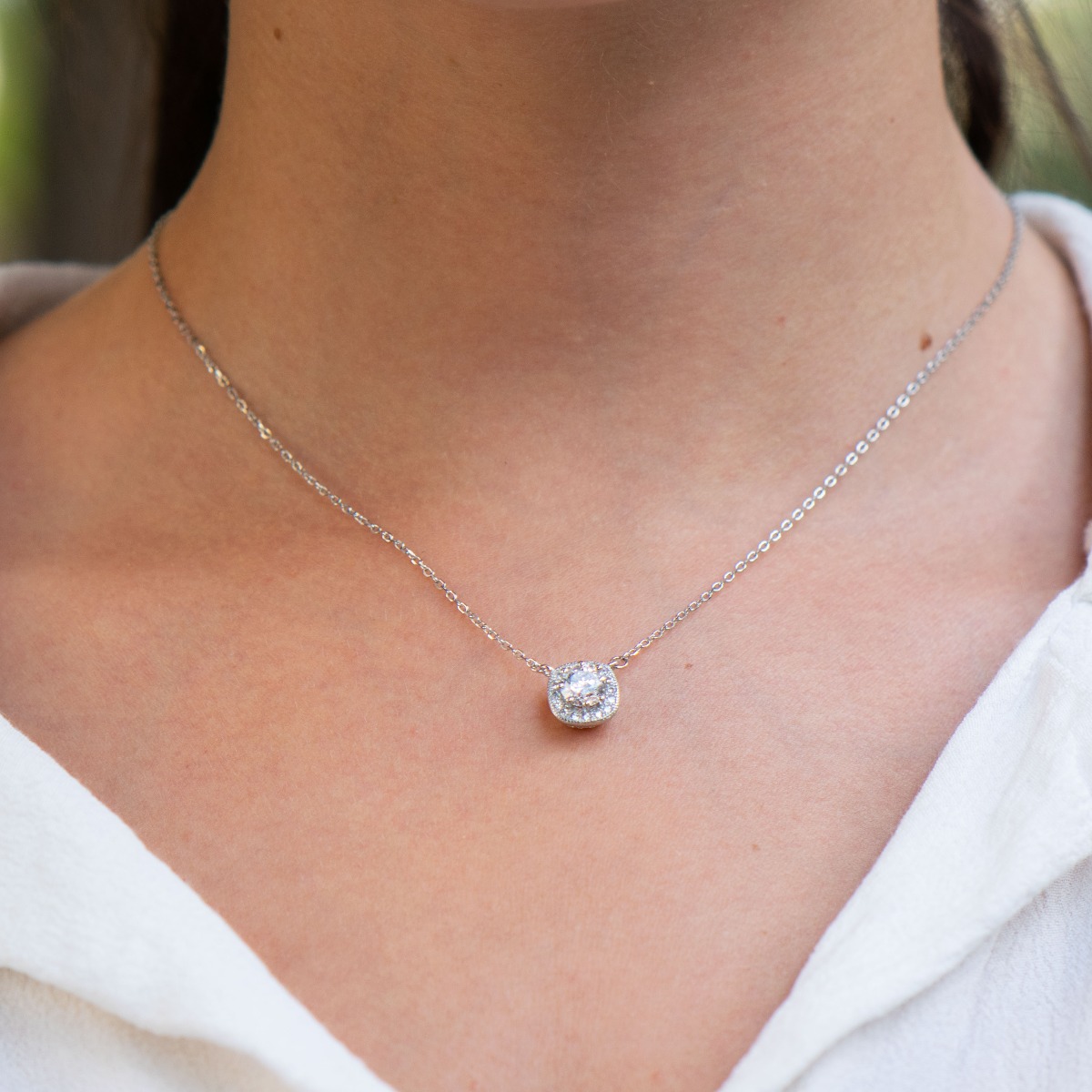 Temptingly crafted women's necklace in fine rhodium silver with exquisite hardware and countless sparkling zircons encircling a larger center stone.