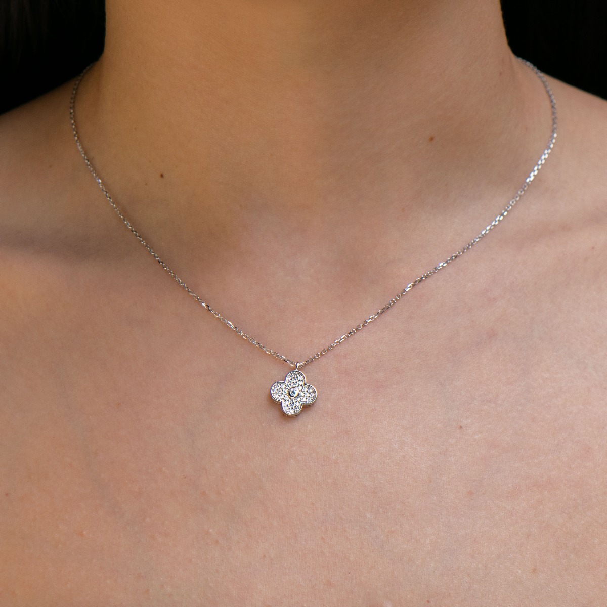 Elegant women's necklace with a modern design made of rhodium silver. The jewelry has a captivating craftsmanship - a delicate chain of classic braid, which carries a glittering flower of dazzling zircons.