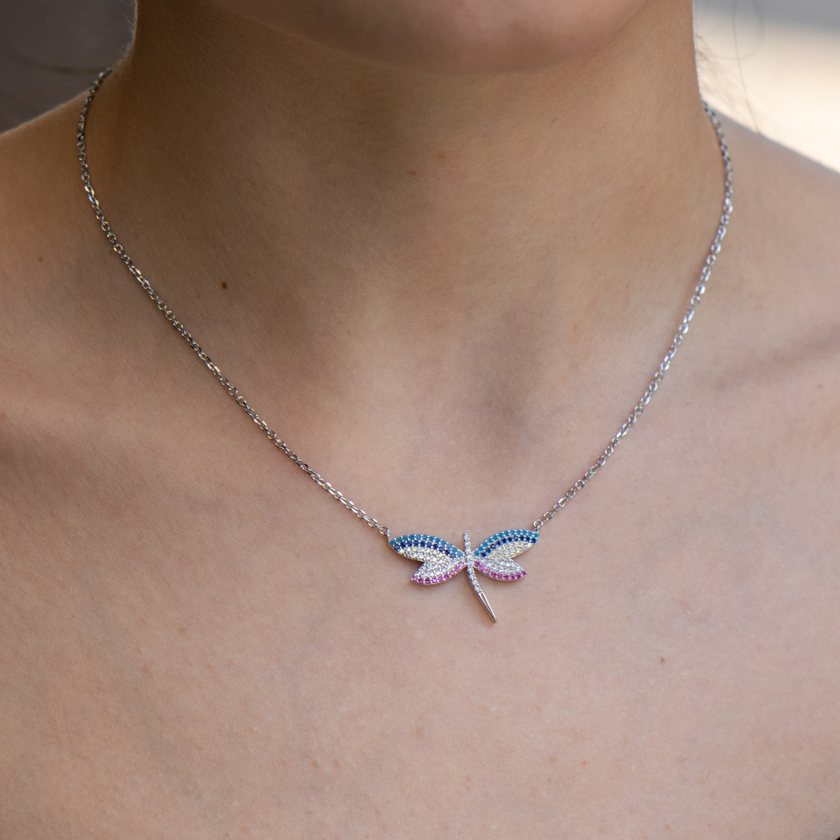 An exquisite silver necklace with a stunningly beautiful dragonfly, with wings delicately decorated with colorful zircons. A suitable gift for any occasion.