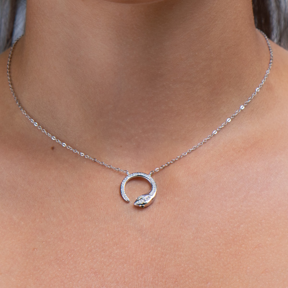 Elegant women's necklace with rhodium silver design. The piece of jewelery has a captivating craftsmanship - a delicate chain holding a delicate element in the shape of a snake, elegantly decorated with sparkling zircons.