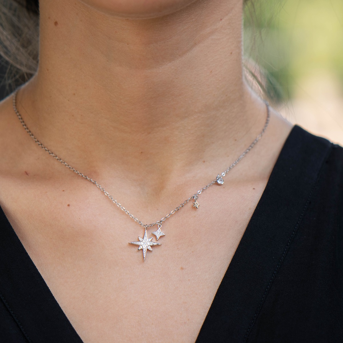 Charming women's necklace made of soft rhodium silver with exquisitely crafted star pendants, asymmetrically placed on one side of the chain.