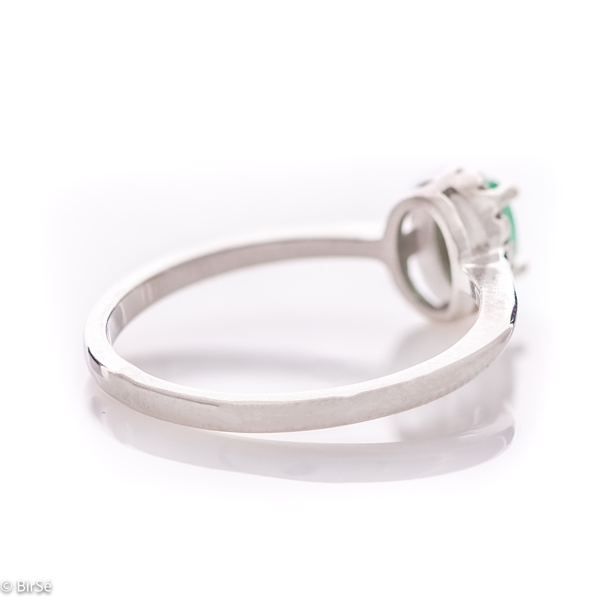 An elegant women's ring with a delicate natural emerald stone, complemented by the sparkle of fine zircons and beautiful craftsmanship entirely in rhodium-plated silver. In a charming set with matching earrings, bracelet and necklace.