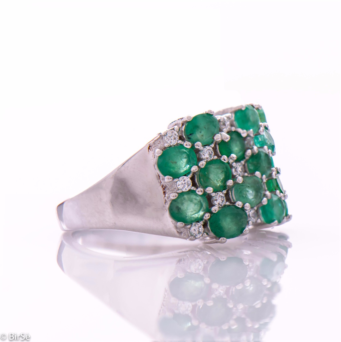 Women's ring with modern craftsmanship, combining numerous fine natural emerald stones, complemented by the sparkle of zircons and made entirely of rhodium-plated silver. In a charming set with matching necklace and earrings.