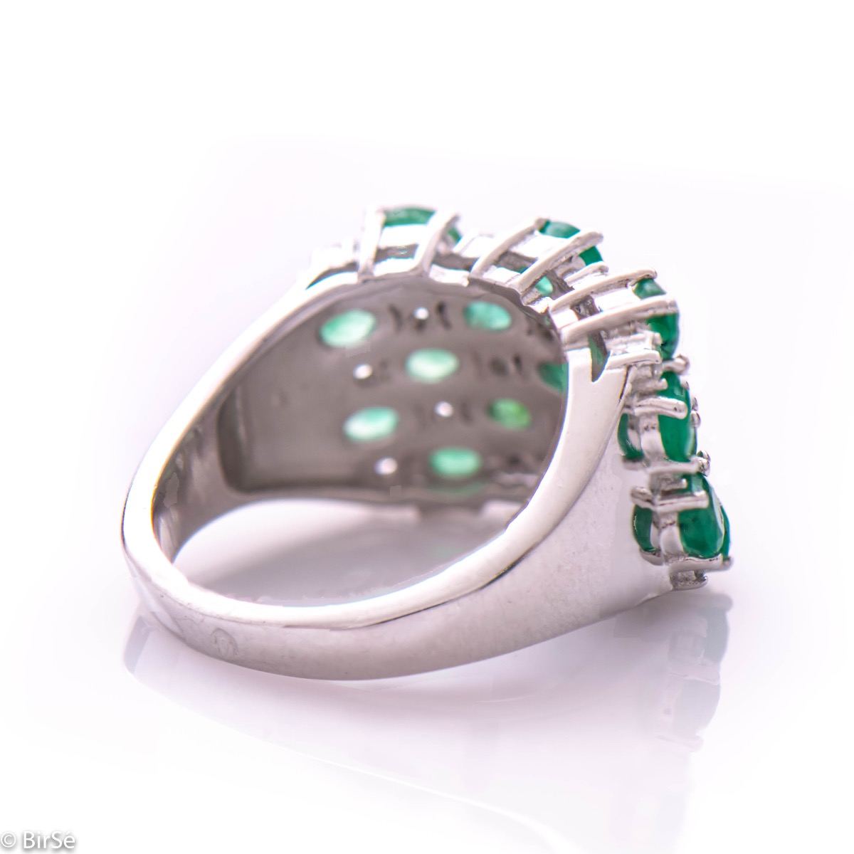 Women's ring with modern craftsmanship, combining numerous fine natural emerald stones, complemented by the sparkle of zircons and made entirely of rhodium-plated silver. In a charming set with matching necklace and earrings.