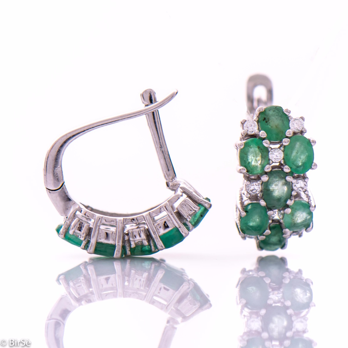 Exquisite ladies' earrings with English fastening and spectacular craftsmanship of delicate rhodium silver, intertwined with fine and numerous natural emerald stones, combined with sparkling zircons. In a charming set with matching necklace and ring.