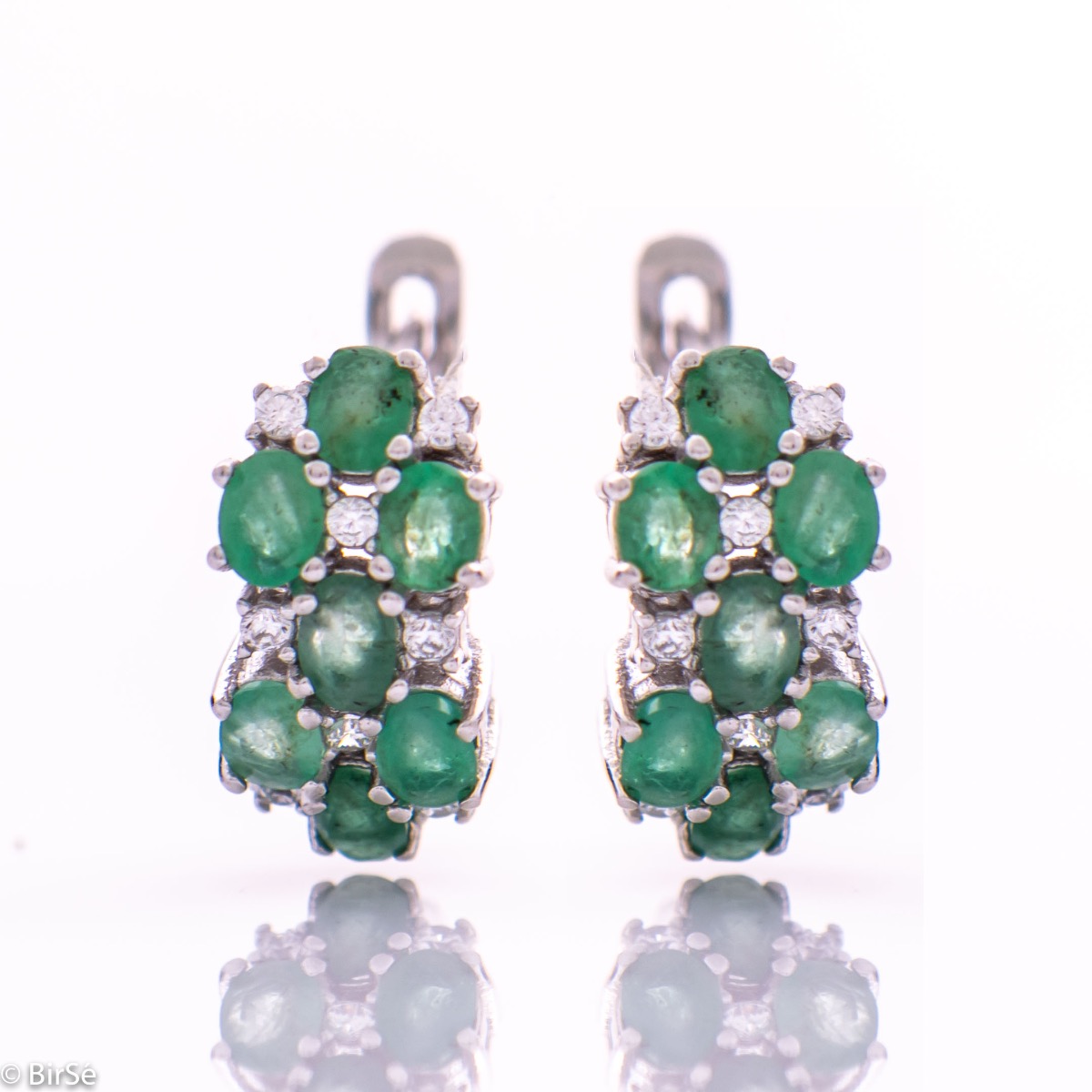 Exquisite ladies' earrings with English fastening and spectacular craftsmanship of delicate rhodium silver, intertwined with fine and numerous natural emerald stones, combined with sparkling zircons. In a charming set with matching necklace and ring.