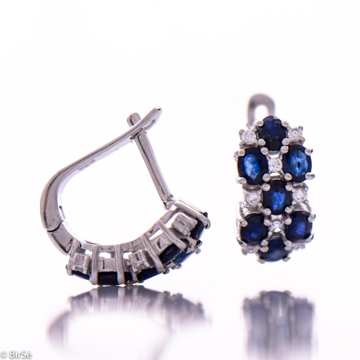 Spectacular ladies' earrings with English clasp, combining numerous natural sapphire stones, intertwined with delicate zircons and made entirely of rhodium-plated silver. In a charming set with matching ring and necklace.