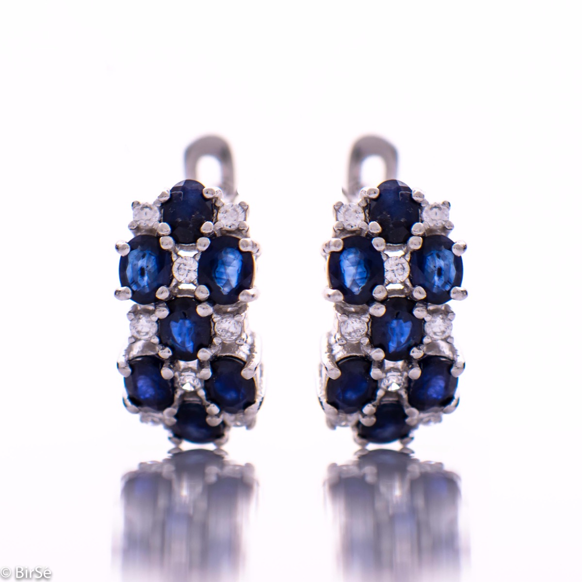 Spectacular ladies' earrings with English clasp, combining numerous natural sapphire stones, intertwined with delicate zircons and made entirely of rhodium-plated silver. In a charming set with matching ring and necklace.