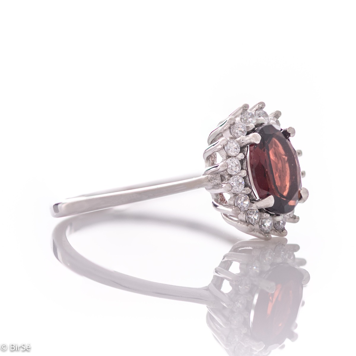 An elegant women's ring with a spectacular workmanship entirely of rhodium-plated silver, combined with a radiant natural garnet and sparkling zircons. Can be combined with earrings and pendant of the same model.