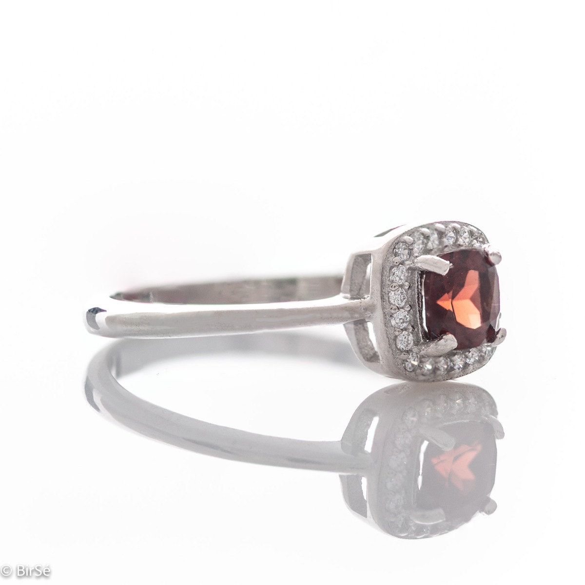 An exquisitely crafted ring of brilliant rhodium-plated silver with interestingly shaped details. A central role is occupied by a magnetic natural garnet, beautifully surrounded by small fine zircons. Can be combined with earrings and pendant from the set