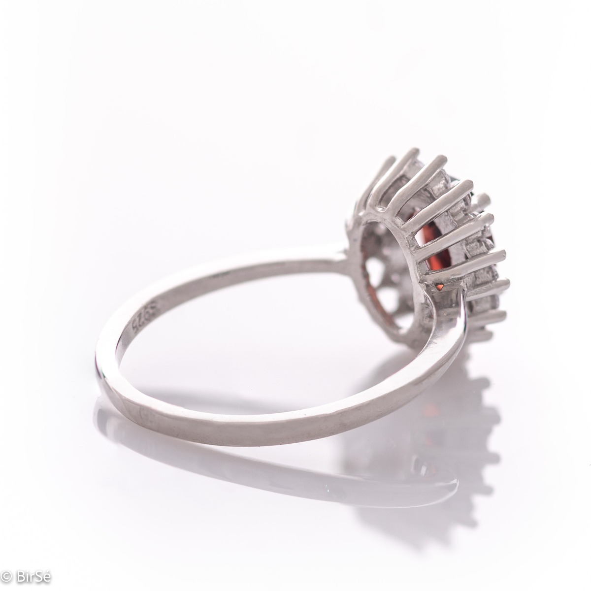 An elegant women's ring with a spectacular workmanship entirely of rhodium-plated silver, combined with a radiant natural garnet and sparkling zircons. Can be combined with earrings and pendant of the same model.