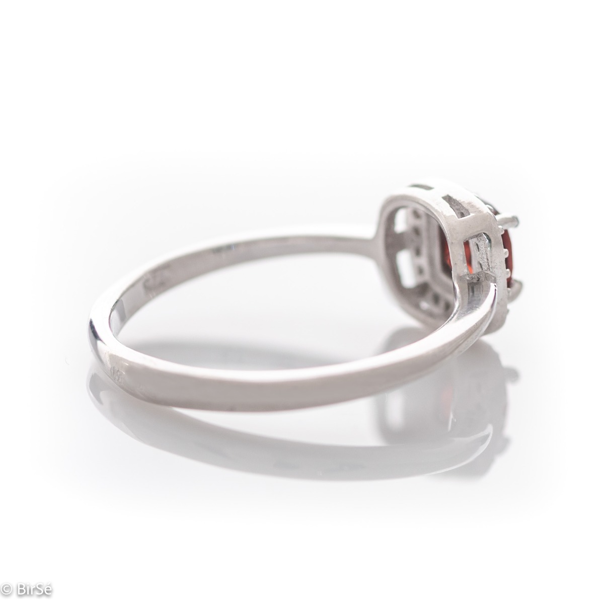 An exquisitely crafted ring of brilliant rhodium-plated silver with interestingly shaped details. A central role is occupied by a magnetic natural garnet, beautifully surrounded by small fine zircons. Can be combined with earrings and pendant from the set