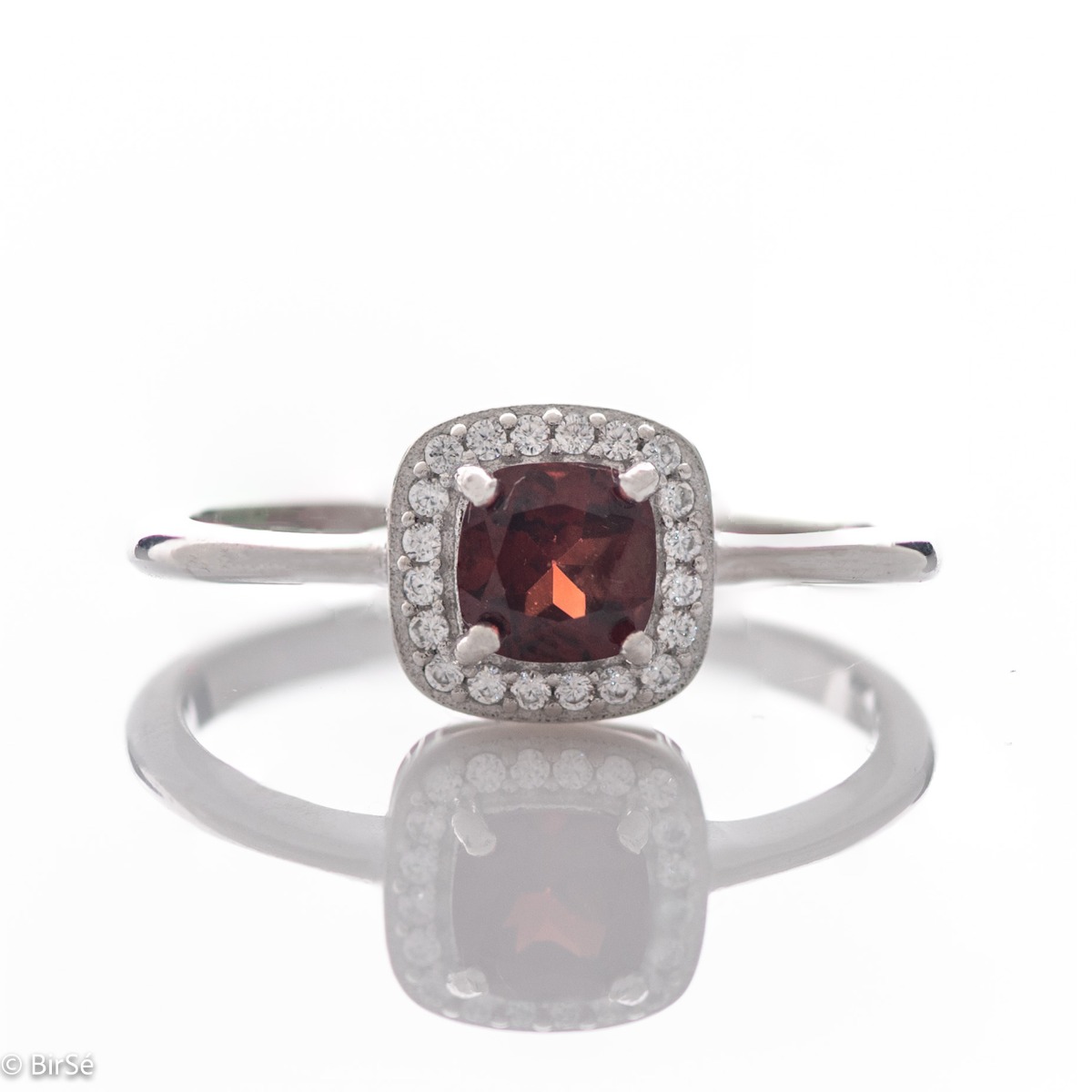 An exquisitely crafted ring of brilliant rhodium-plated silver with interestingly shaped details. A central role is occupied by a magnetic natural garnet, beautifully surrounded by small fine zircons. Can be combined with earrings and pendant from the set