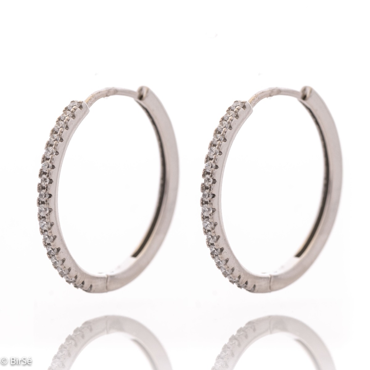 Feminine and tempting earrings cast in rhodium silver in the shape of a ring. The look of the delicate earrings is completed by sparkling zircons that perfectly complement the jewelry. The fastening is with a piercing, for greater convenience and comfort.