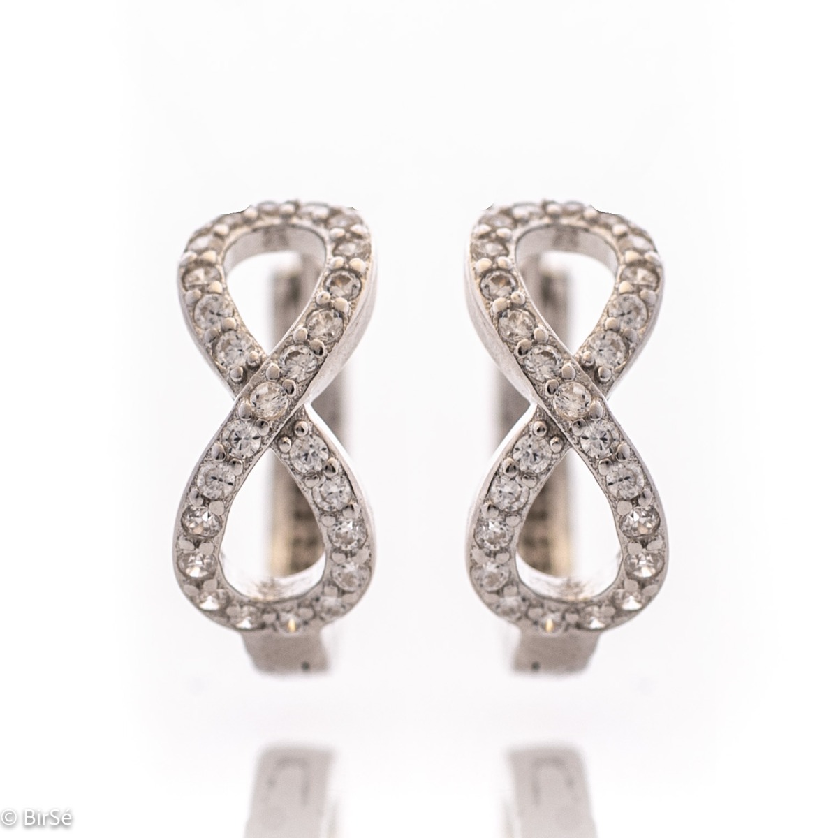 Delicate ladies' earrings - rings made of rhodium-plated silver with a comfortable English clasp. The front side of the earrings is shaped like an exquisite infinity, carefully decorated with zircons.