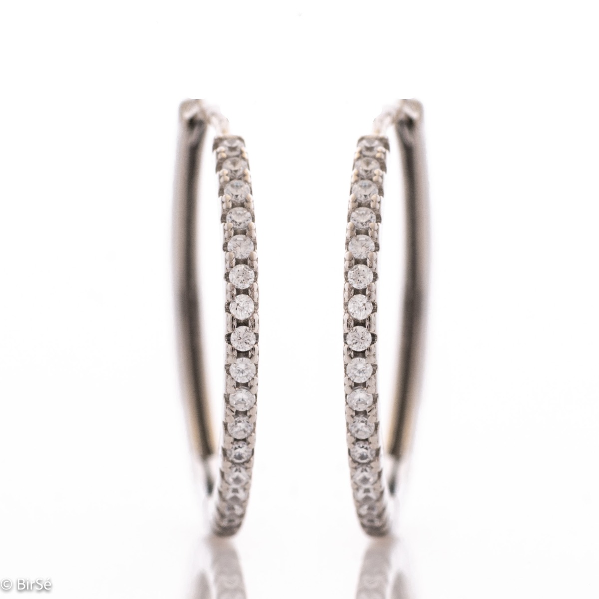 Feminine and tempting earrings cast in rhodium silver in the shape of a ring. The look of the delicate earrings is completed by sparkling zircons that perfectly complement the jewelry. The fastening is with a piercing, for greater convenience and comfort.